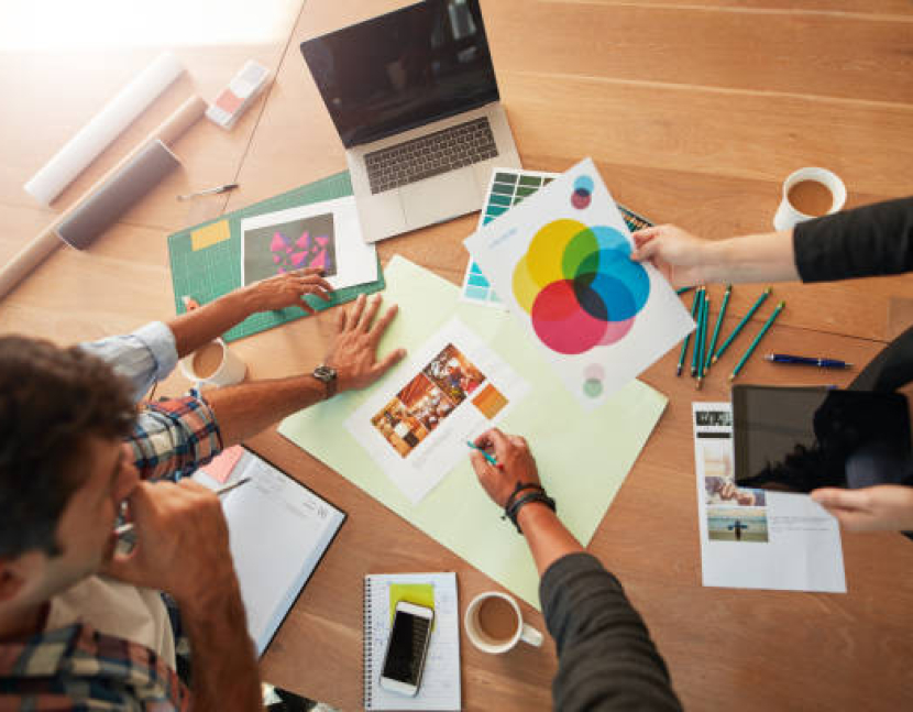 Top view shot of young designers discussing the color palette. Creative team brainstorming around table working together on new project.